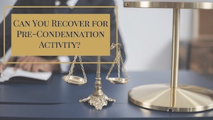 A lawyer's desk with scales in front and a lawyer's signing a paperwork behind it.