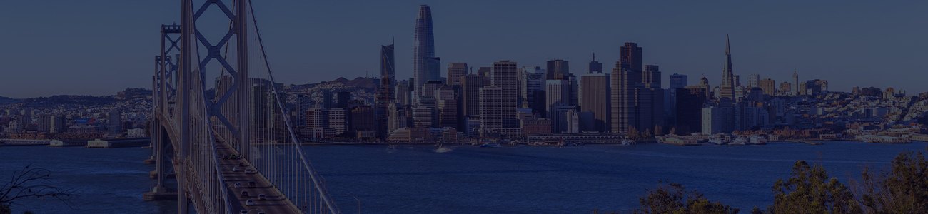 Bay Bridge leading to the San Francisco skyline during daytime with cars on the bridge.