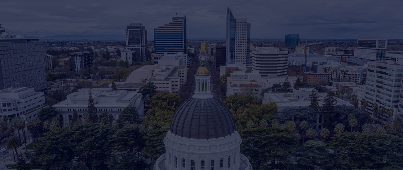 Aerial view of the California State Capitol building with surrounding downtown Sacramento cityscape.