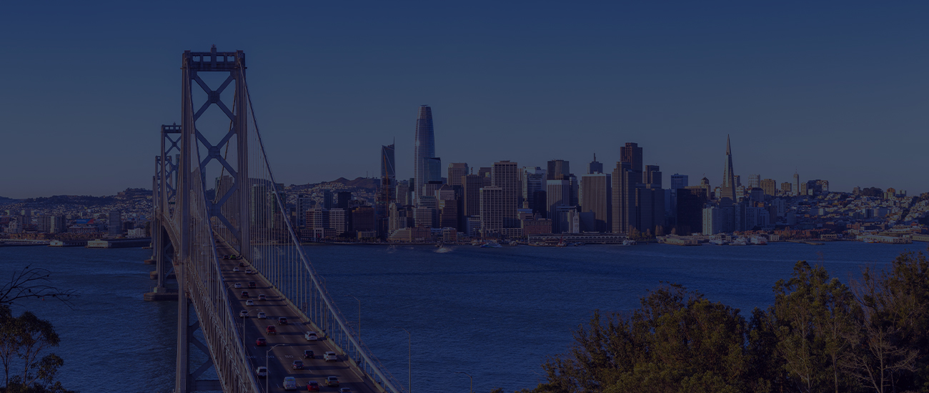 Bay Bridge leading to the San Francisco skyline during daytime with cars on the bridge.